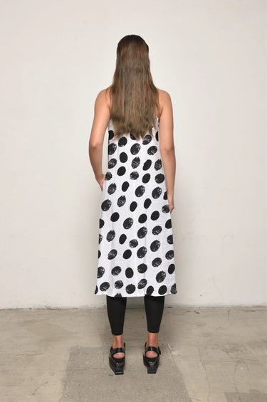 Woman wearing a white dress with black polka dots against a plain background