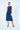 Woman wearing a navy blue dress with oversized pockets on a white background