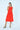 Woman wearing a red dress with oversized pockets on a white background
