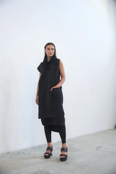 Woman wearing a black sleeveless dress against a white background