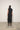 Person wearing a black sleeveless dress against a white wall.