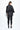 Person wearing a black textured jacket and leggings on a white background