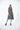 A female model wearing a linen gray sleeveless knee-length dress with vertical stripes and round neckline, standing against a white background.