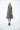 A female model wearing a linen gray sleeveless knee-length dress with vertical stripes and round neckline, standing against a white background.
