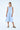 Woman wearing a light blue dress with oversized pockets on a white background