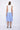A female model wearing a sleeveless, hand-dyed blue and white knee-length dress with side seam pockets and a racerback design.