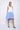 A female model wearing a sleeveless, hand-dyed blue and white knee-length dress with side seam pockets and a racerback design.