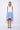 A female model wearing a sleeveless, hand-dyed blue and white knee-length dress with side seam pockets and a racerback design.