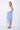 A female model wearing a sleeveless, hand-dyed blue and white knee-length dress with side seam pockets and a racerback design.