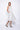 A woman wearing a light grey sleeveless knee-length dress with pockets in a white background setting.