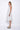 A woman wearing a light grey sleeveless knee-length dress with pockets in a white background setting.
