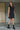A woman wearing a black sleeveless mini dress with a high collar, pockets and front zipper.