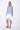 A female model wearing a sleeveless, hand-dyed blue and white ombre dress with a hi-low hem and racerback.
