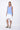 A female model wearing a sleeveless, hand-dyed blue and white ombre dress with a hi-low hem and racerback.