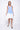 A female model wearing a sleeveless, hand-dyed blue and white ombre dress with a hi-low hem and racerback.
