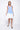 A female model wearing a sleeveless, hand-dyed blue and white ombre dress with a hi-low hem and racerback.