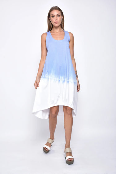 A female model wearing a sleeveless, hand-dyed blue and white ombre dress with a hi-low hem and racerback.