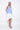 A female model wearing a sleeveless, hand-dyed blue and white knee-length dress with side seam pockets, asymmetrical hem and a racerback design.