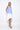 A female model wearing a sleeveless, hand-dyed blue and white knee-length dress with side seam pockets, asymmetrical hem and a racerback design.