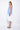 A female model wearing a sleeveless, hand-dyed blue and white knee-length dress with side seam pockets, asymmetrical hem and a racerback design.