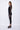 Person wearing a black outfit with sheer sleeves on a white background
