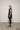 A woman modeling a sleeveless black tunic with a draped cowl neck and Asymmetrical hem, paired with black leggings.