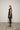 A woman modeling a sleeveless black tunic with a draped cowl neck and Asymmetrical hem, paired with black leggings.