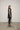 A woman modeling a sleeveless black tunic with a draped cowl neck and Asymmetrical hem, paired with black leggings.