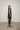 A woman modeling a sleeveless black tunic with a draped cowl neck and Asymmetrical hem, paired with black leggings.