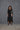 Person wearing a black outfit with a textured background