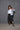 A model wearing a white boxy shirt with black strokes and black culotte pants.