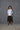 A model wearing a white boxy shirt with black strokes and black culotte pants.