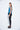 A female model wearing a Teal sleeveless top, uneven hem, Black leggings and Black sandals against a white background