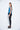 A female model wearing a Teal sleeveless top, uneven hem, Black leggings and Black sandals against a white background