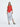 A female model wearing a Red sleeveless top, uneven hem, Black horizontal striped asymmetrical skirt and sandals against a white background