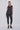 Woman wearing a black sleeveless top and leggings on a white background