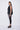Person wearing a black sleeveless top and leggings on a white background