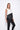 A female model wearing a Black and white sleeveless top, uneven hem, Black leggings and Black sandals against a white background