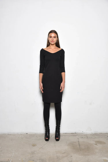 Woman wearing a black dress with scoop neckline against a white background