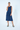 Woman wearing a navy blue dress with oversized pockets on a white background