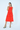 Woman wearing a red dress with oversized pockets on a white background