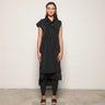 Person wearing a black sleeveless dress with a hood against a plain background