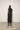 Person wearing a black sleeveless dress against a white wall.