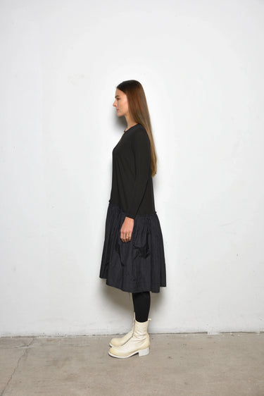 Woman wearing a black dress and white boots against a white background