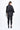 Person wearing a black textured jacket and leggings on a white background