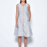 A female model wearing a sleeveless knee-length dress with horizontal black stripes and round neckline, standing against a white background.