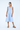 Woman wearing a light blue dress with oversized pockets on a white background