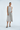 Woman wearing a light gray sleeveless dress with oversized pockets on a white background