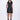 A woman wearing a black sleeveless mini dress with a high collar, pockets and front zipper.