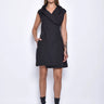 A woman wearing a black sleeveless mini dress with a high collar, pockets and front zipper.
